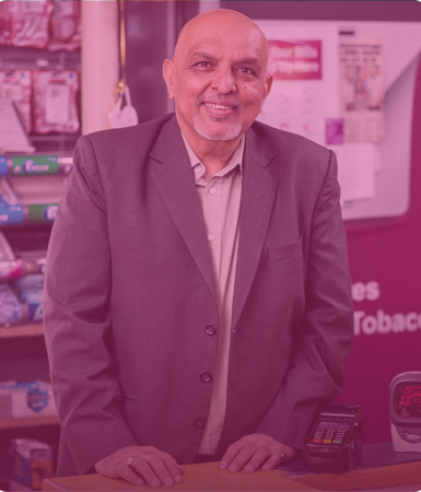 Man smiling at camersa behind counter 